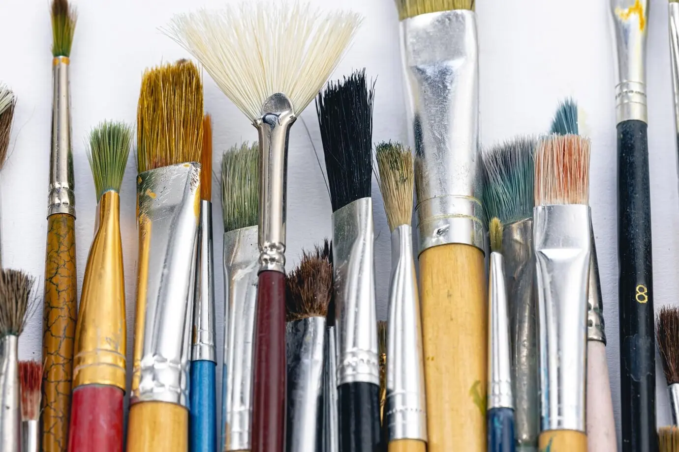 Nahaufnahme von alten Malpinseln vor weißem Hintergrund.